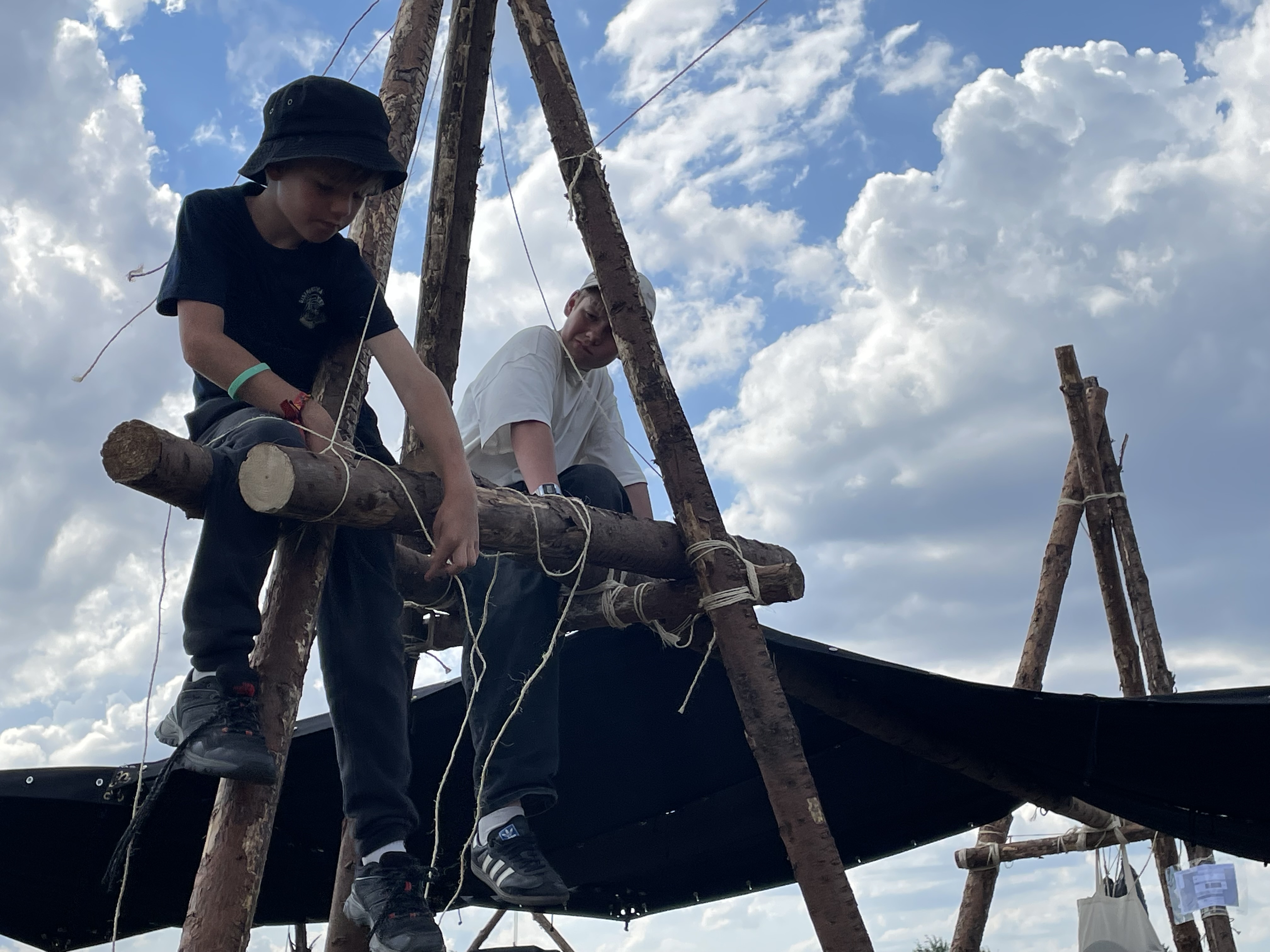 Zwei Kinder bauen mit Holzstangen und Seil